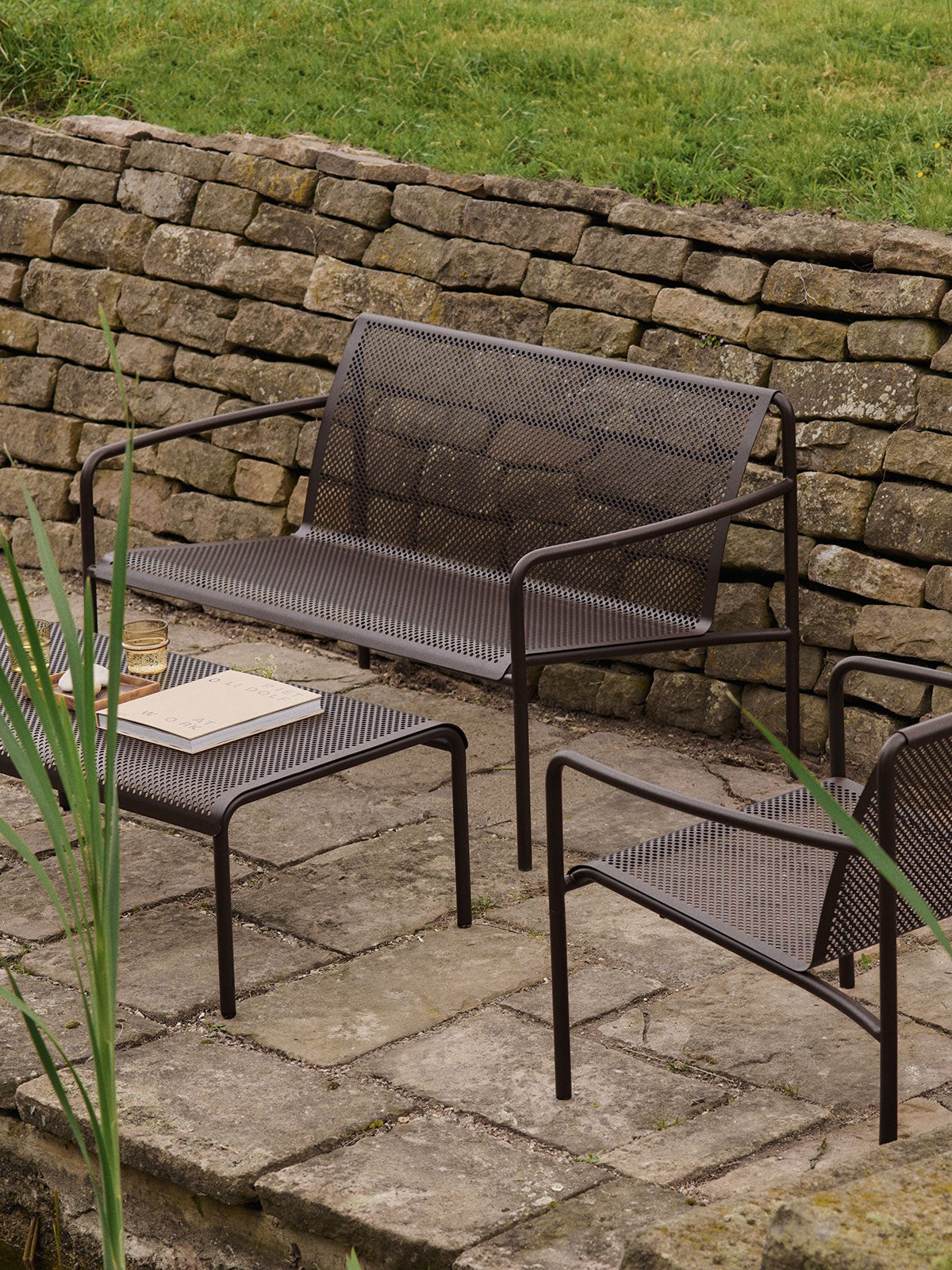 Dapple Loungesofa, Dapple Loungestol og Dapple Loungebord 57x57 i farven Dark Chocolate som en loungegruppe på en stenbelagt udeplads