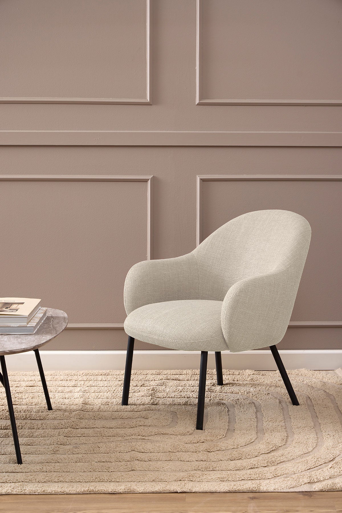Spencer Loungestol i stoffet Basel Beige som står på et beige uldtæppe