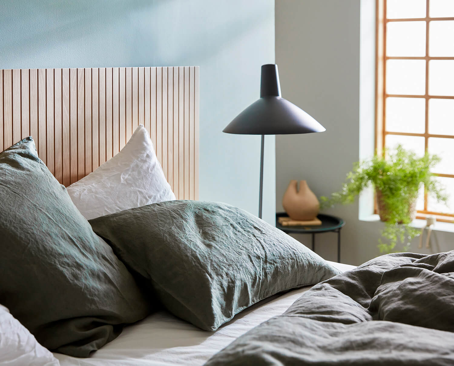 En ubredt seng i et solrigt soveværelse